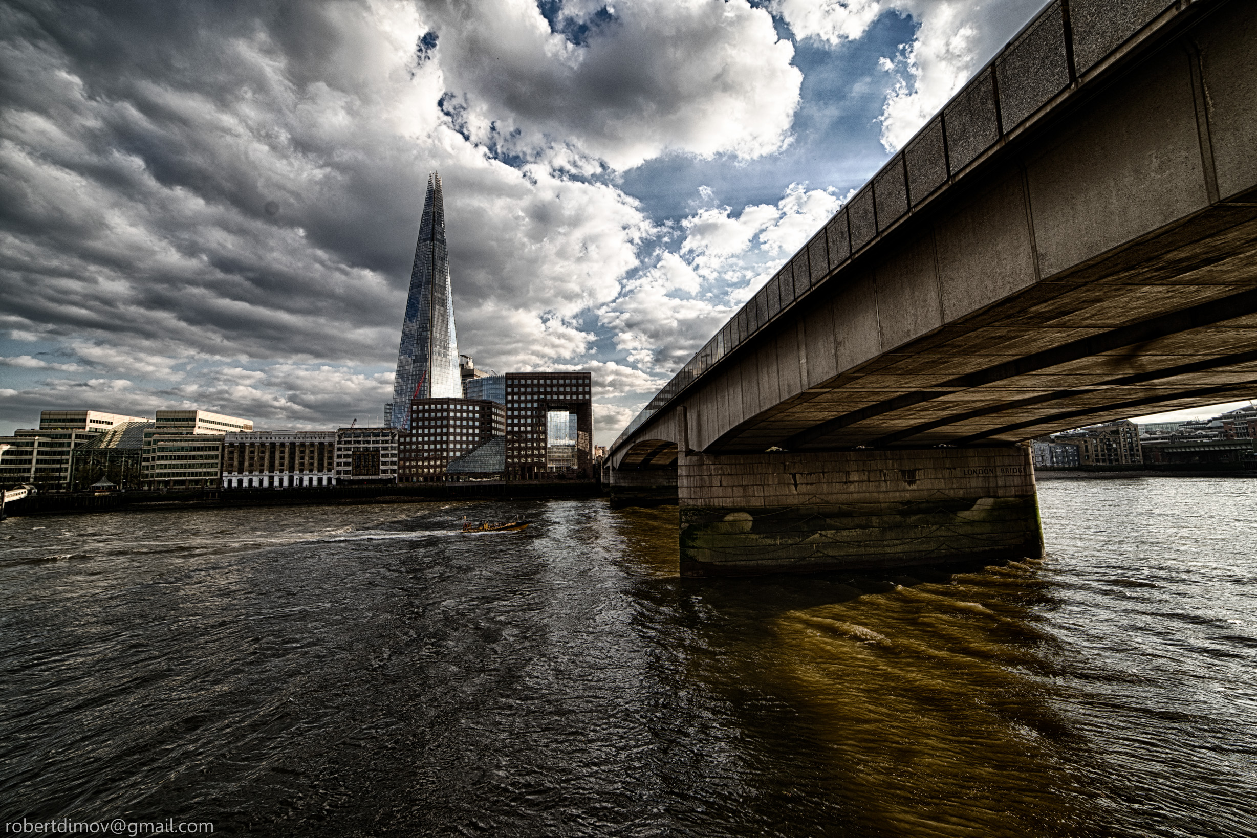 bridge spans a river, with a tall building rising in the background against a clear sky