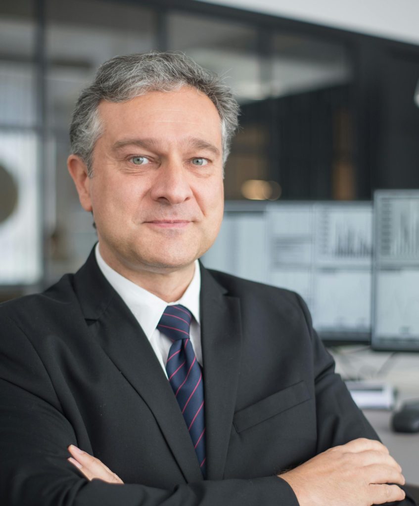 Corporate professional with arms crossed in modern office, symbolizing leadership and confidence.